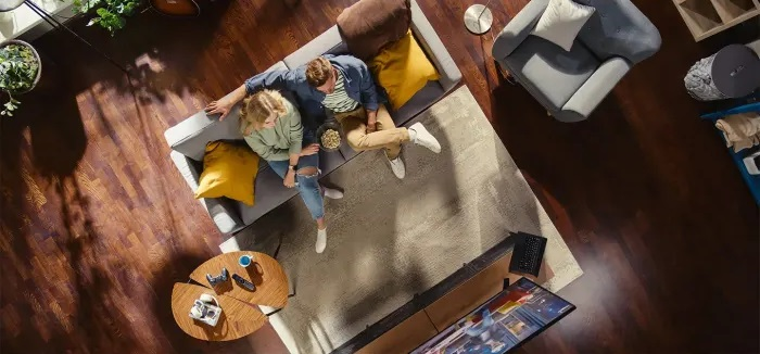 Widok z góry na parę na sofie oglądającą TV, z popcornem.