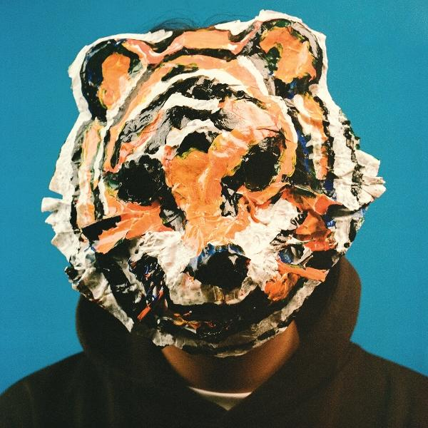 Person trägt Tigermaske aus Papier. Blauer Hintergrund.