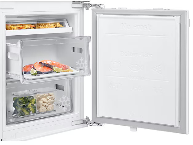 Wnętrze lodówki z produktami spożywczymi: makaronem, łososiem i brokułami.