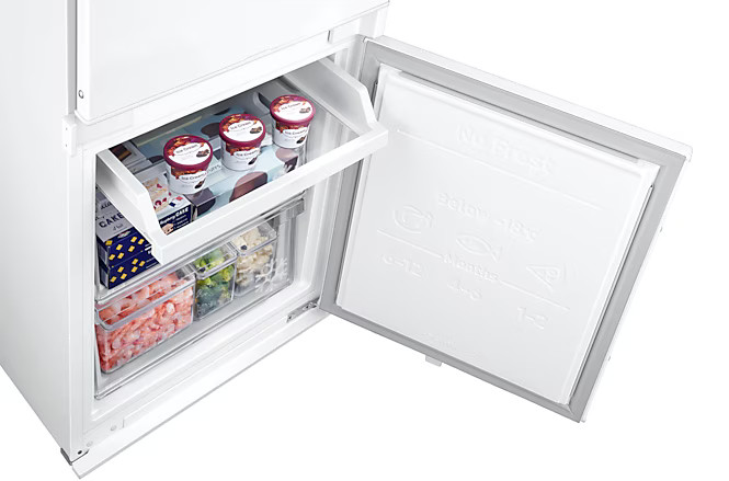 Biała lodówka z otwartymi drzwiami, ukazująca produkty spożywcze i pojemniki wewnątrz.