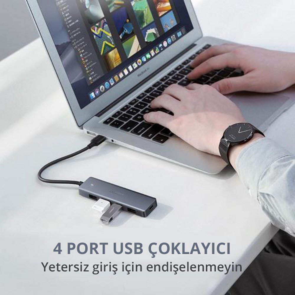 Bir kişi, USB hub'ı olan bir dizüstü bilgisayar kullanıyor. Hub'da bir USB sürücüsü ve diğer bağlantı noktaları var.
