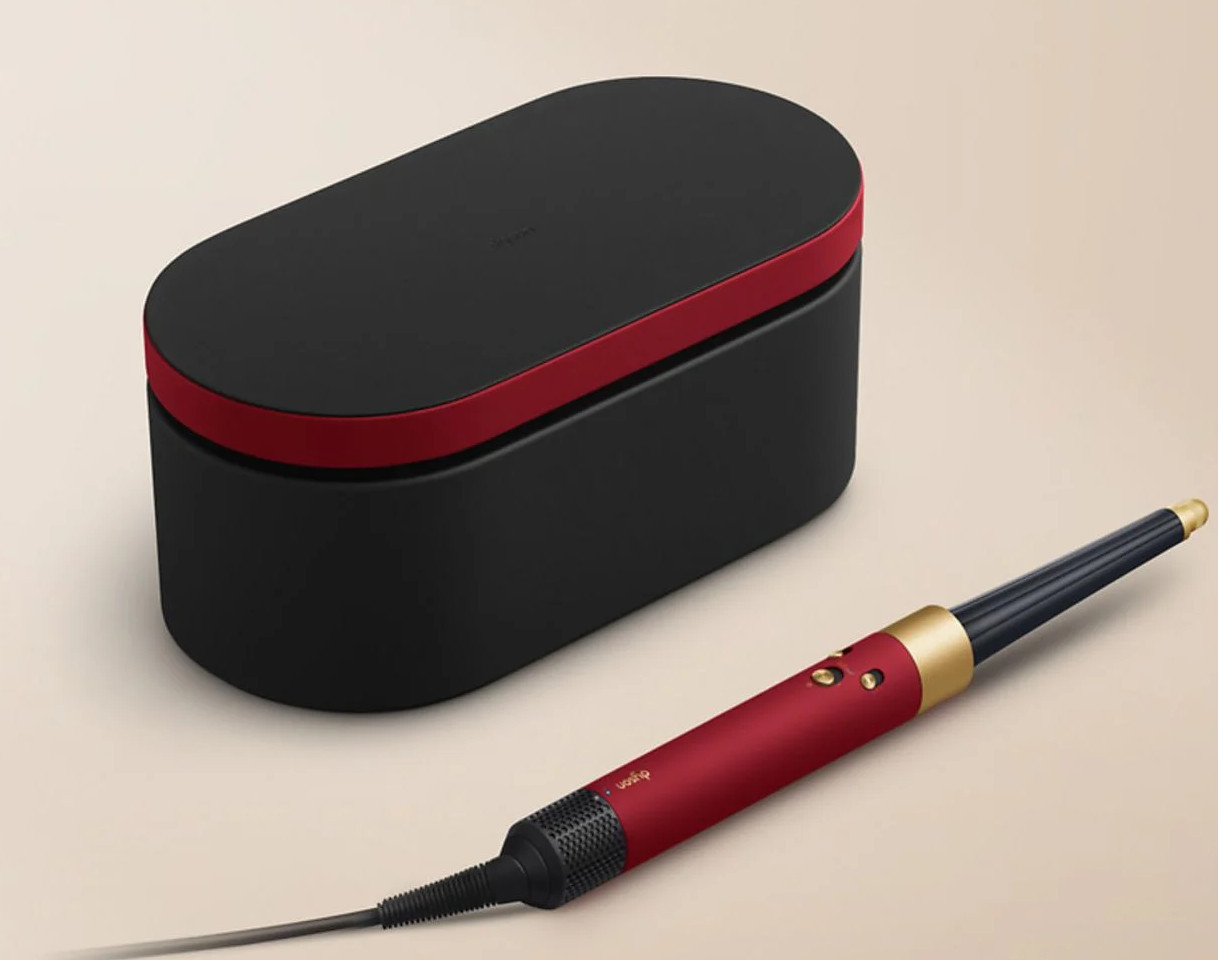 Czarna walizka z czerwonym wykończeniem i czerwoną lokówką obok.