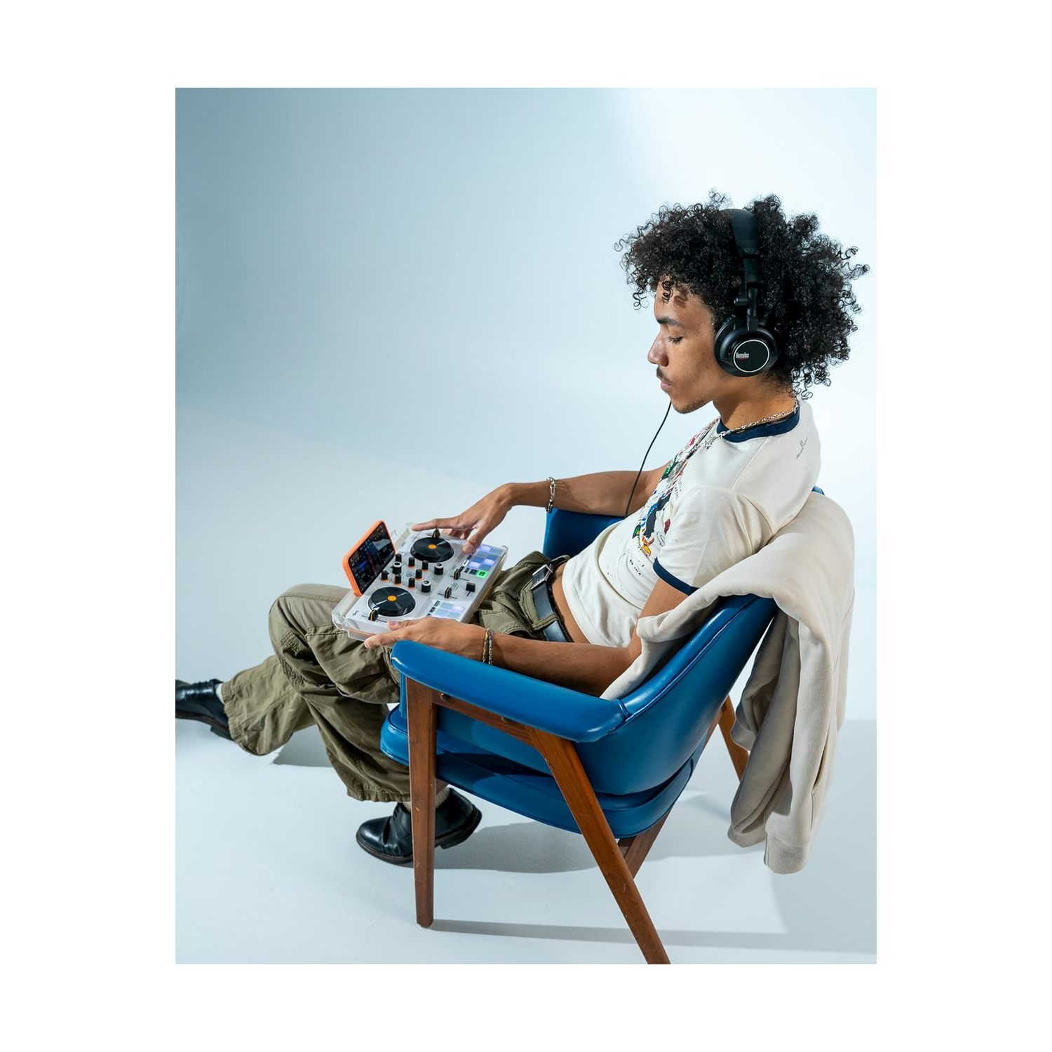 Eine Person mit Kopfhörern und einem Controller sitzt in einem blauen Stuhl.