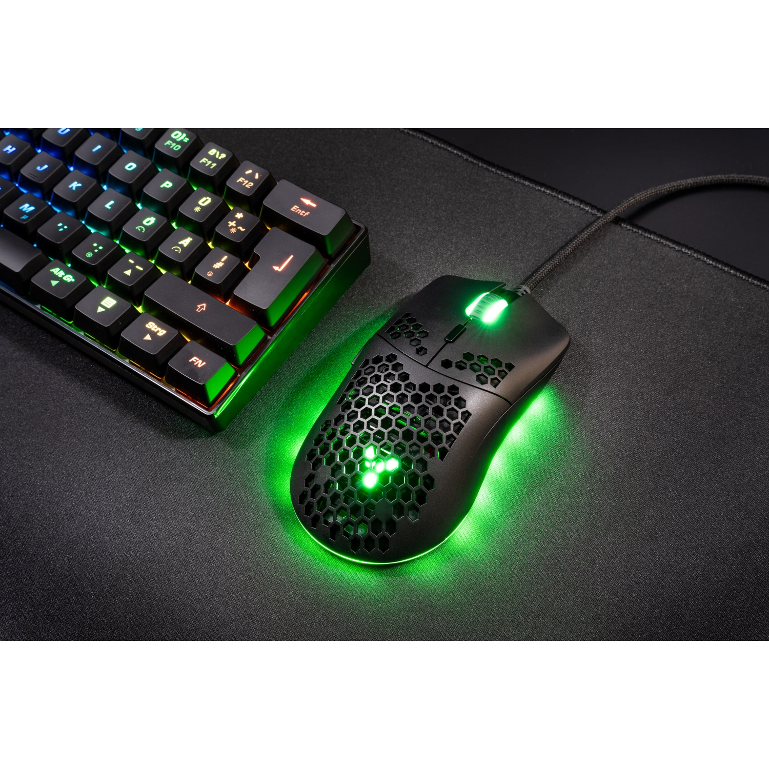 Black gaming mouse and keyboard with green lighting on a black mat.