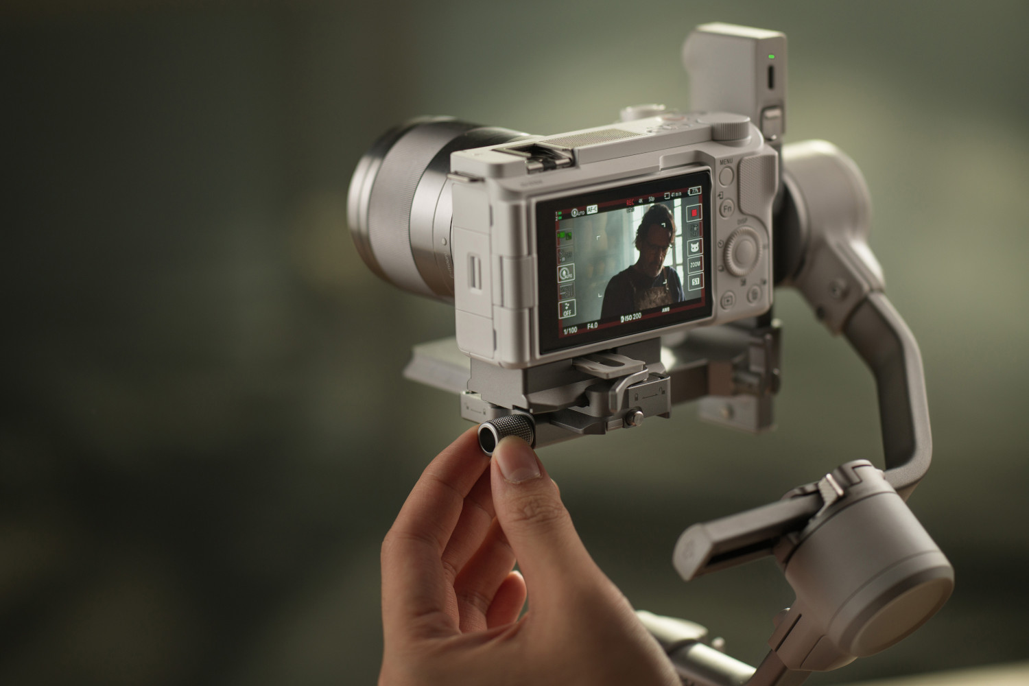 Osoba reguluje śrubę na stabilizatorze kamery. Ekran z podglądem wideo.