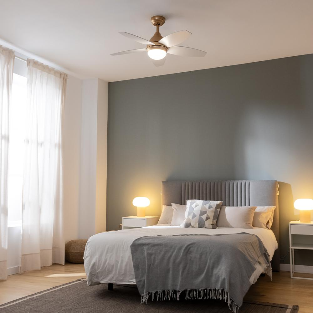 Un dormitorio con cama, mesitas de noche y ventilador de techo.
