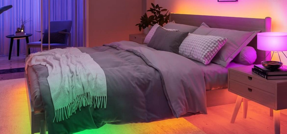 Sypialnia z łóżkiem, szafkami nocnymi i nastrojowym, kolorowym oświetleniem LED.