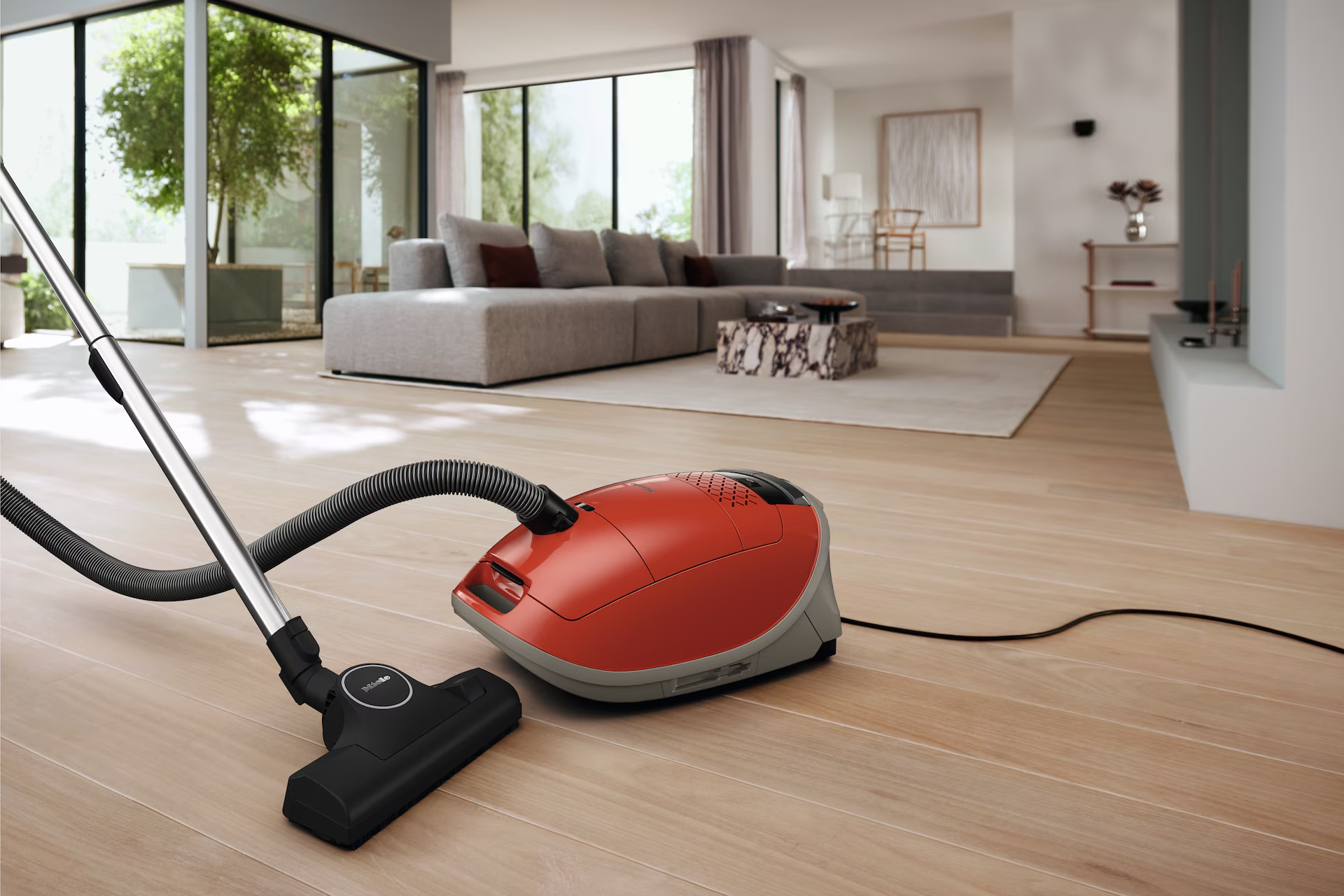 Un salon moderne avec un aspirateur, un canapé et de grandes fenêtres.