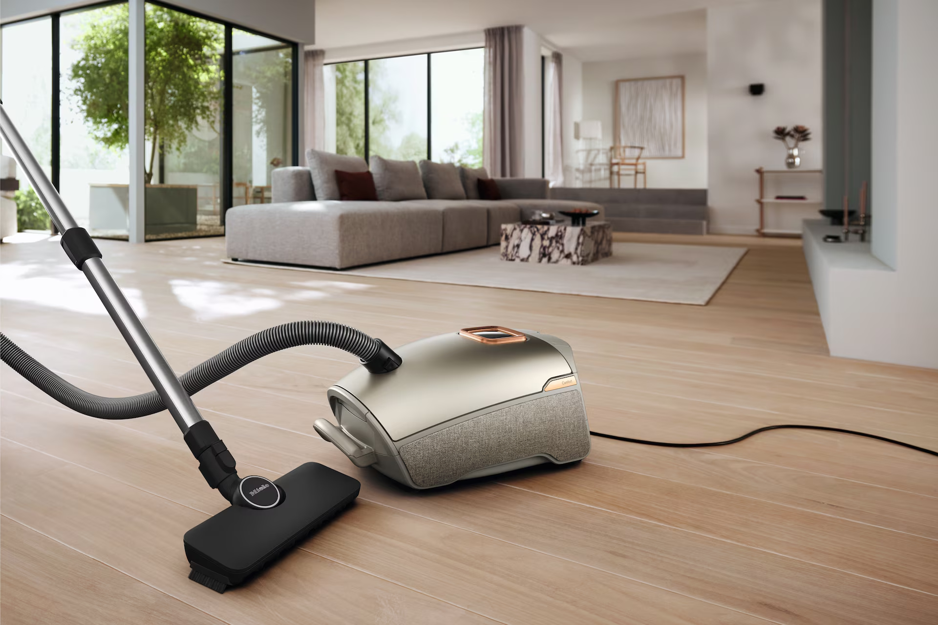 Aspirateur sur parquet dans salon moderne. Tuyau et brosse visibles.