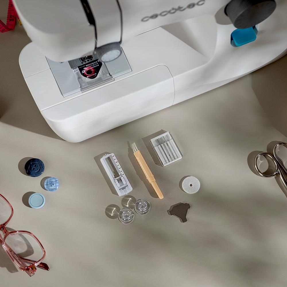 Máquina de coser y herramientas de costura sobre una superficie clara. Incluye tijeras, hilo y botones.