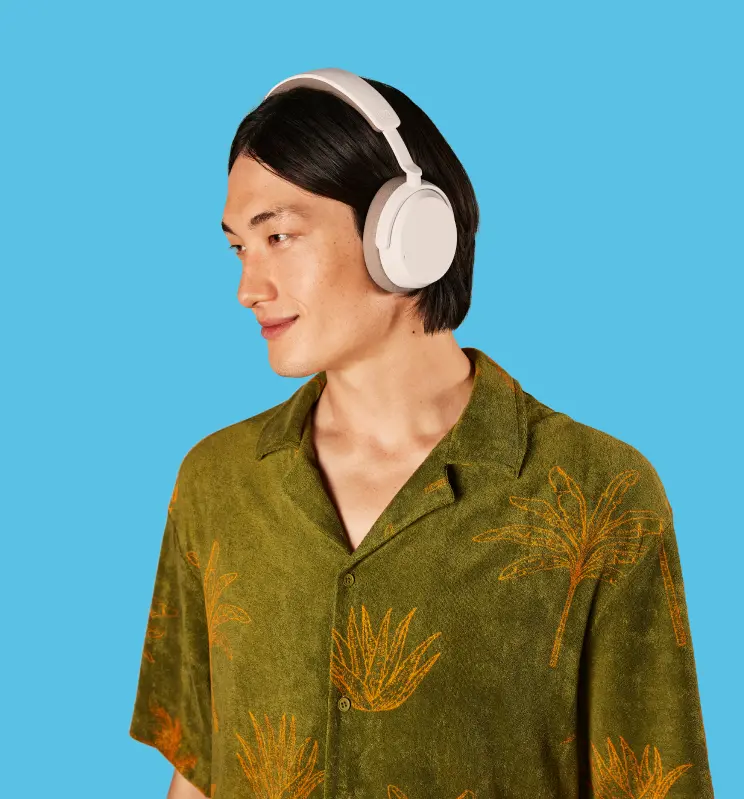 Uomo con cuffie bianche, camicia verde con palme, guarda a destra.