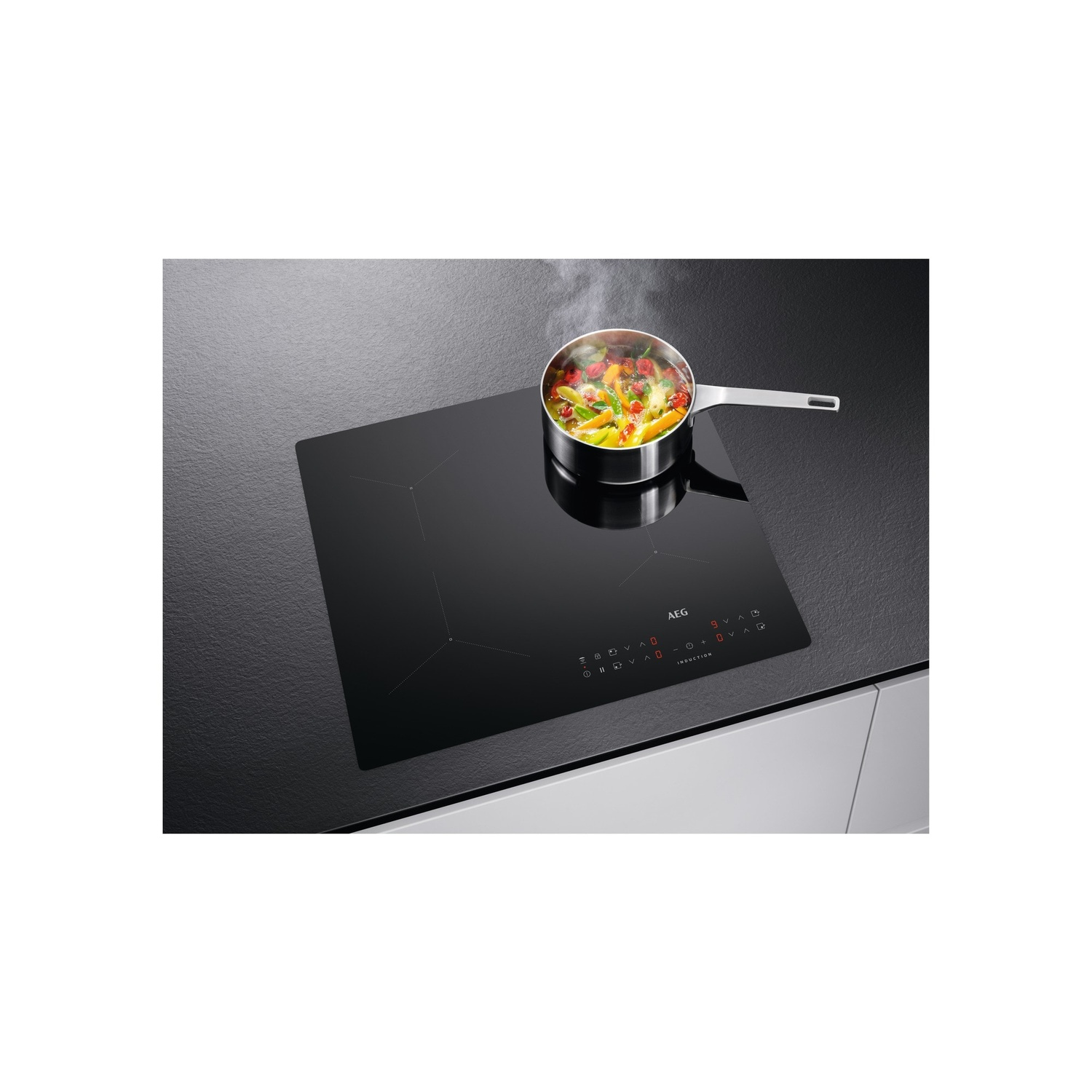 Een zwarte inductiekookplaat met een pan met eten dat op een brander kookt. Het oppervlak is glanzend.