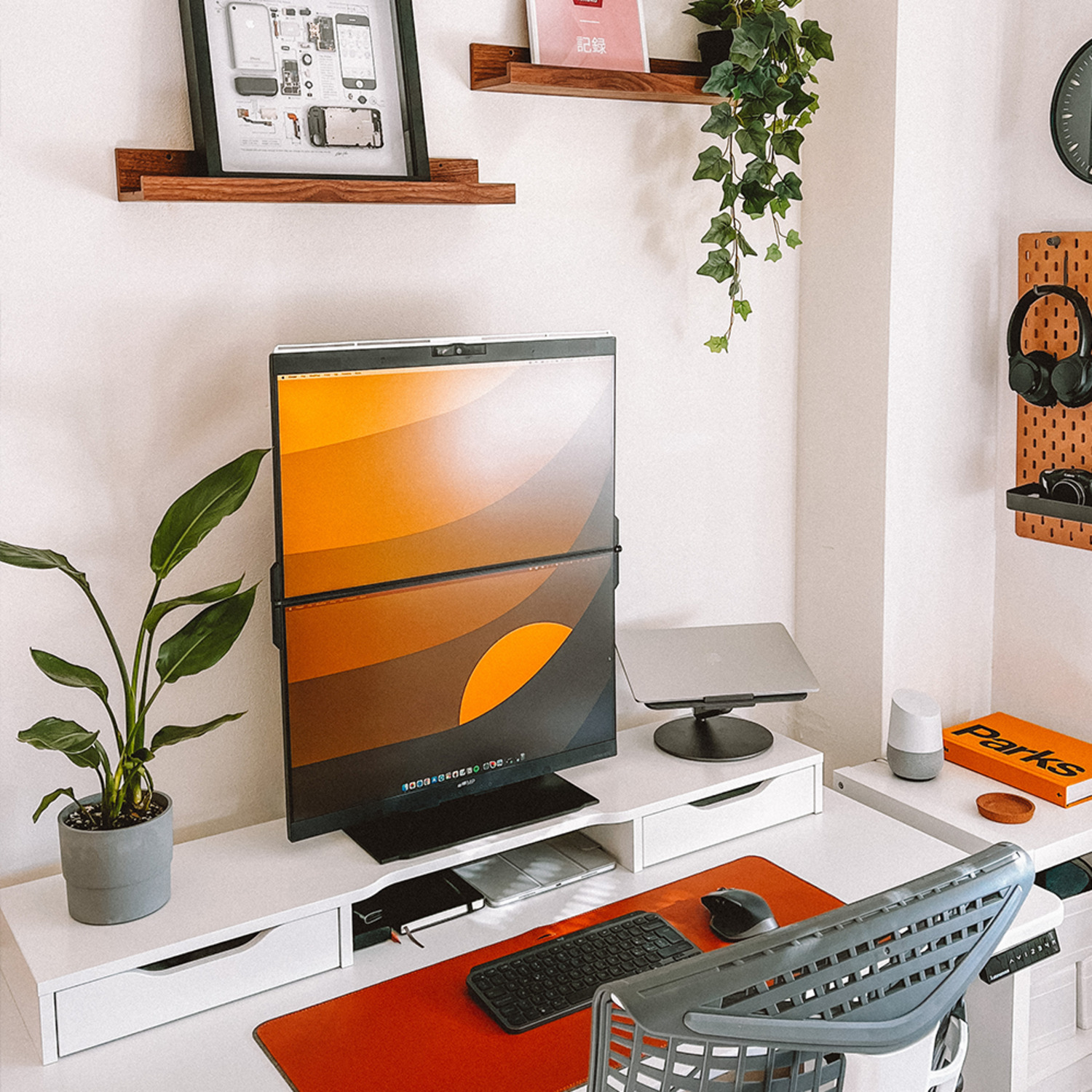A modern desk setup with a monitor, plants, and accessories.