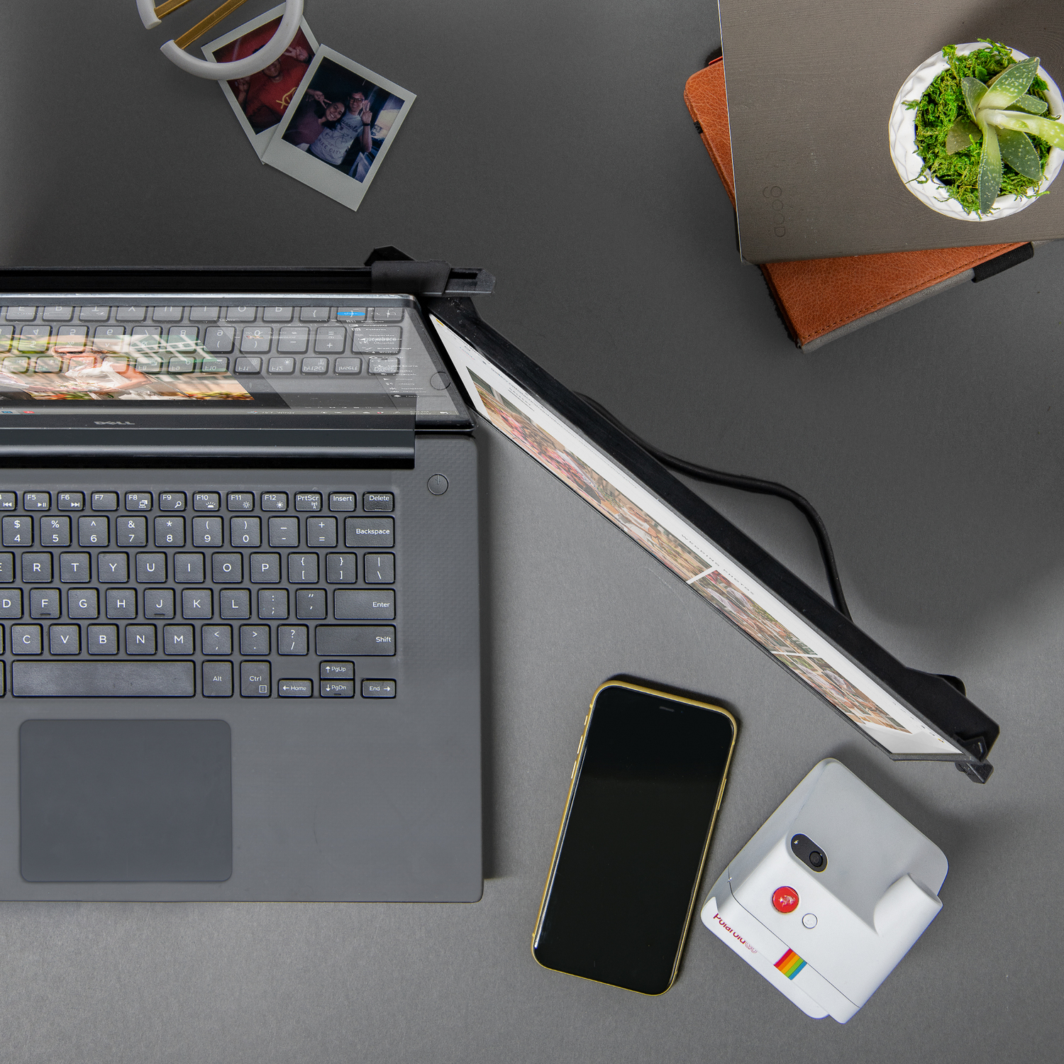 Un ordinateur portable avec un appareil photo instantané blanc, un téléphone et d'autres objets.