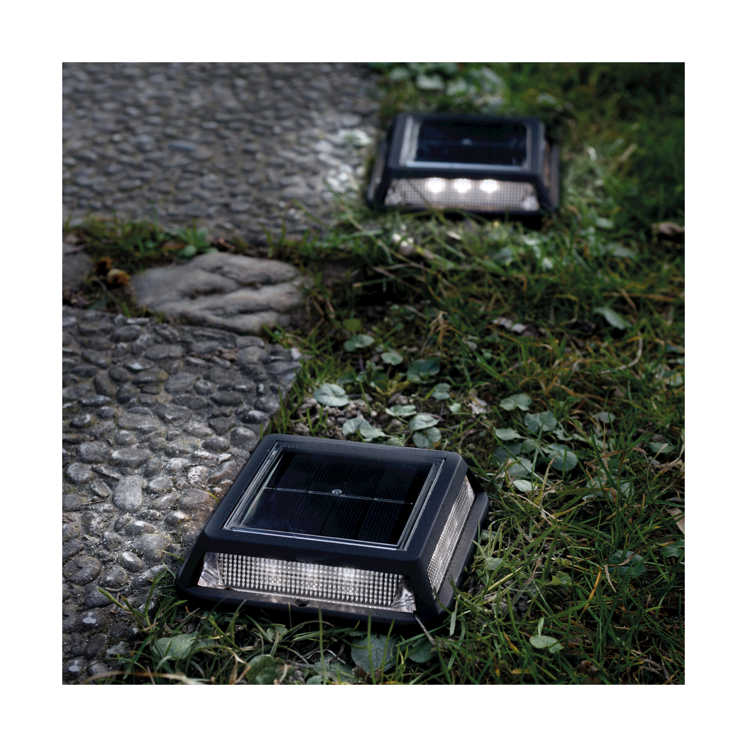 Due luci solari da giardino su un sentiero di pietra.