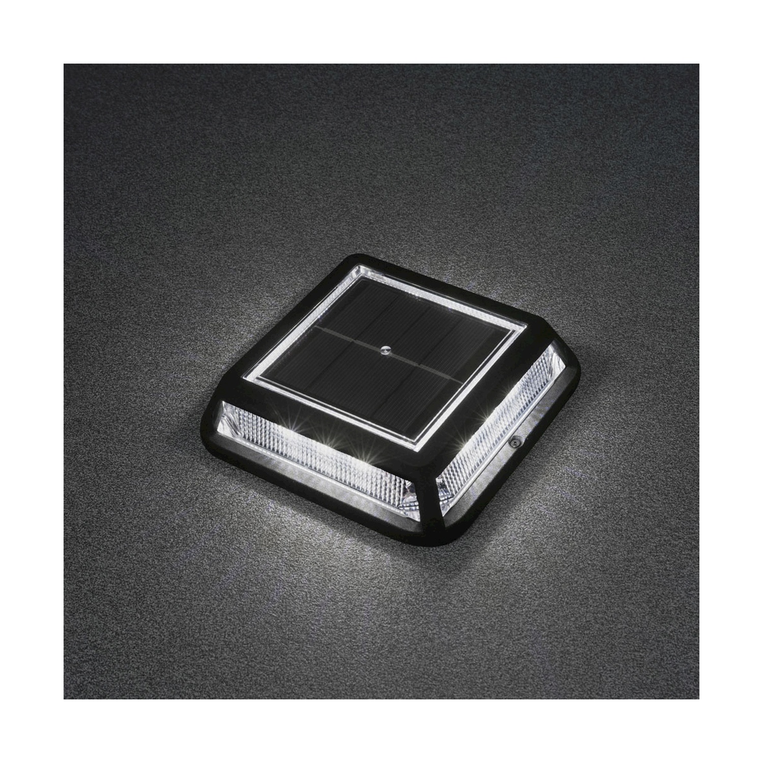 Pannello solare quadrato nero per illuminazione sentieri su superficie grigio scuro strutturata.