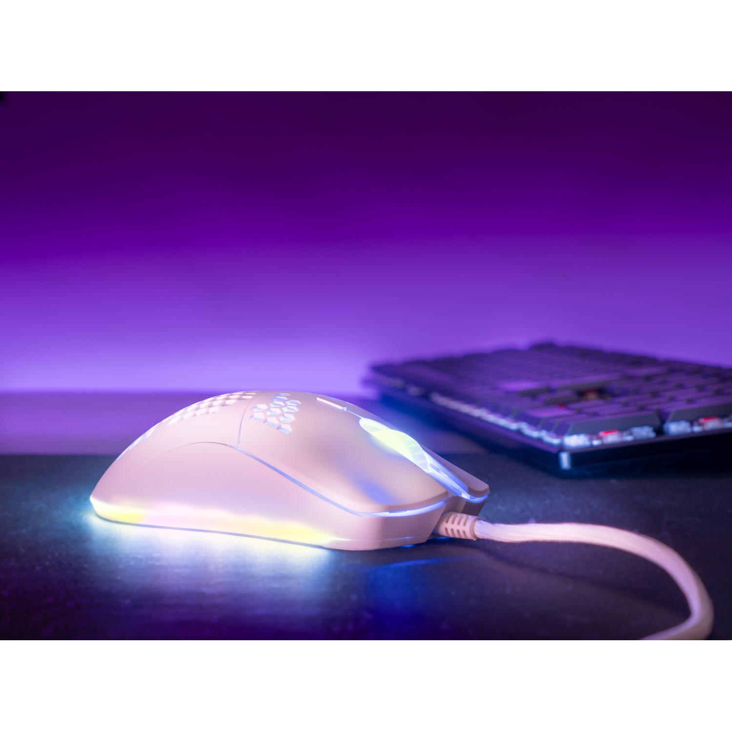A white gaming mouse with RGB lighting and a keyboard in the background.