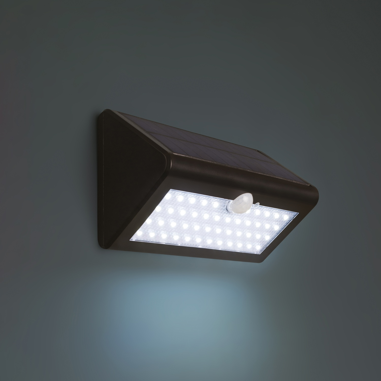 Luce di sicurezza solare nera montata su parete blu scuro, con luci LED bianche.