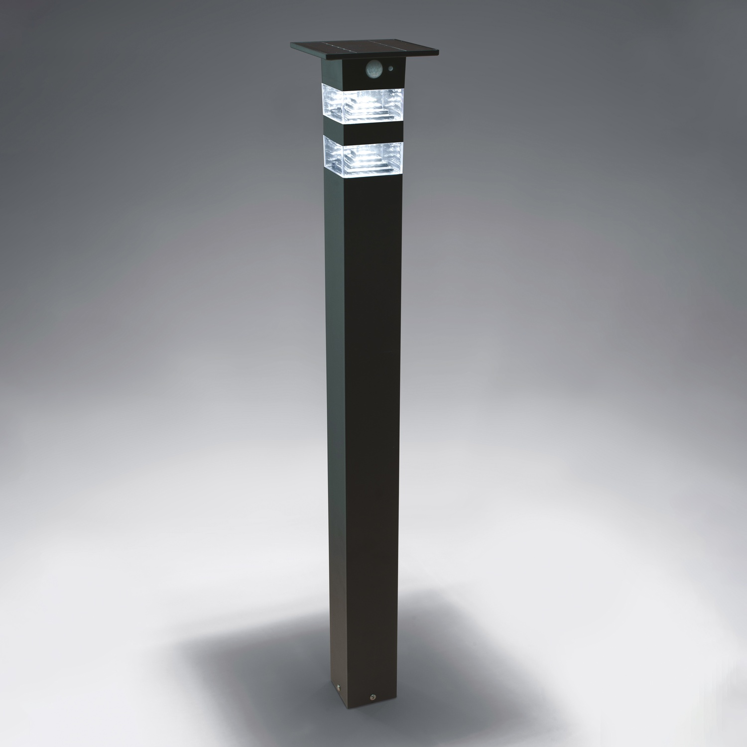Un palo della luce nero ad energia solare con una sezione superiore trasparente e illuminata.