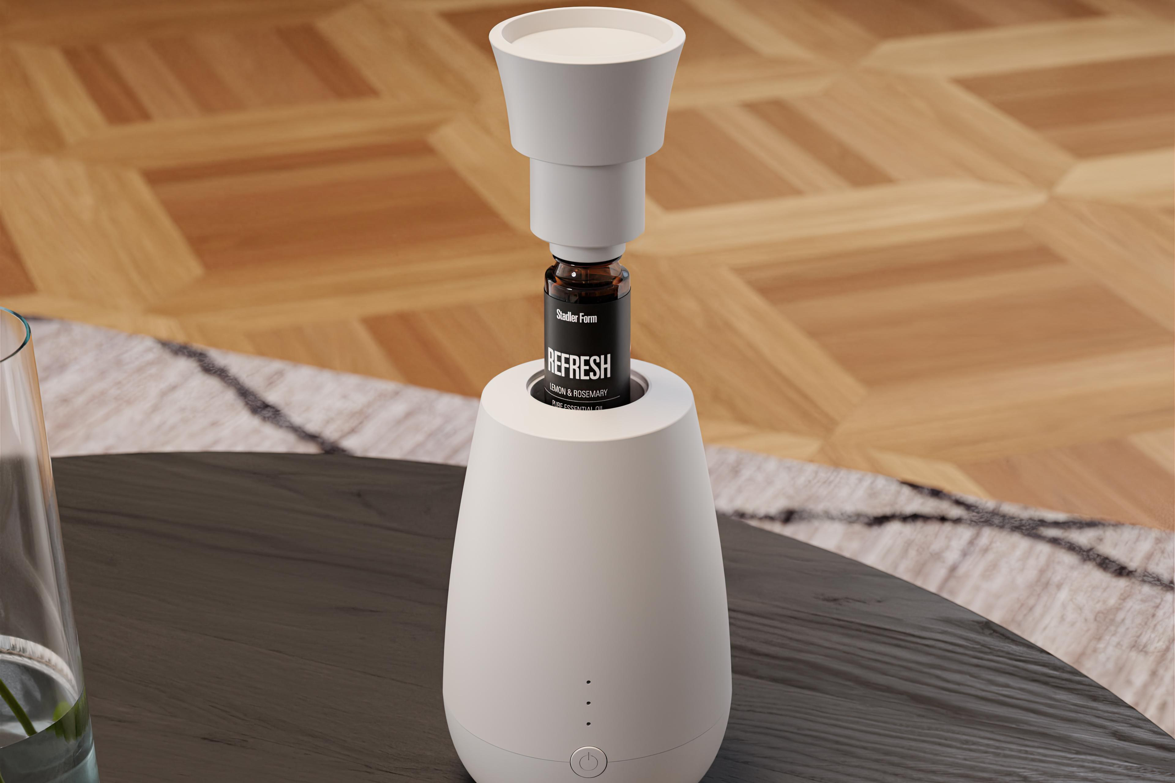 Weißer Diffusor mit dunkler Flasche. Auf einem Tisch mit Holzboden platziert.