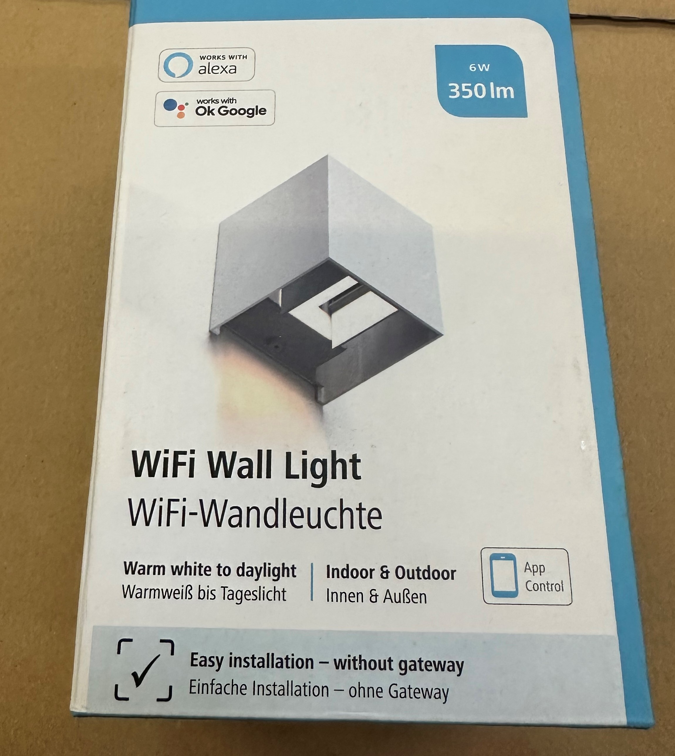 Białe i srebrne pudełko z napisem 'WiFi Wall Light'. Pudełko ma obraz światła.