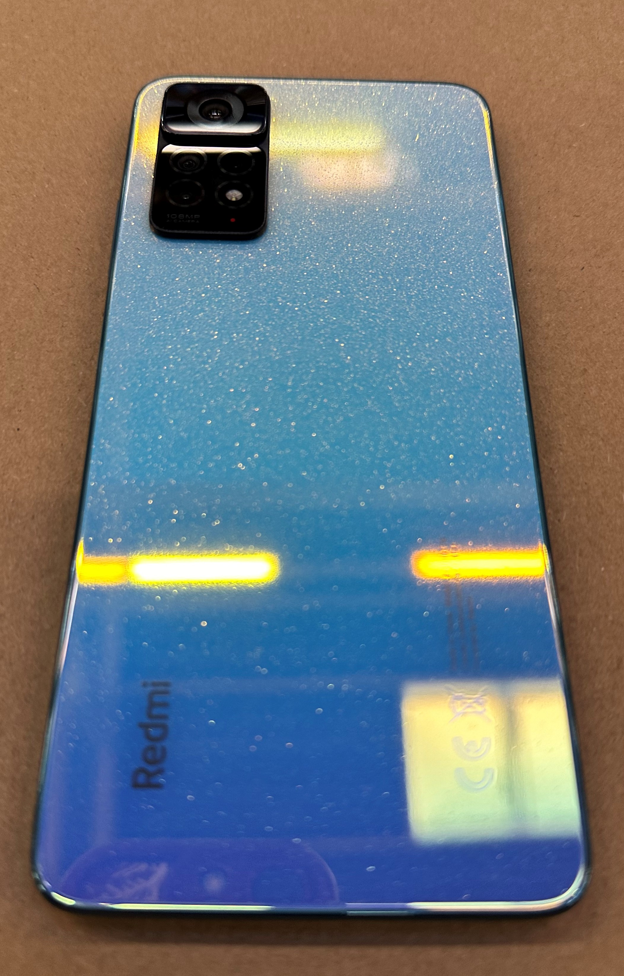 Niebieski gradient na tylnej części telefonu, pokazujący moduł aparatu i logo Redmi.