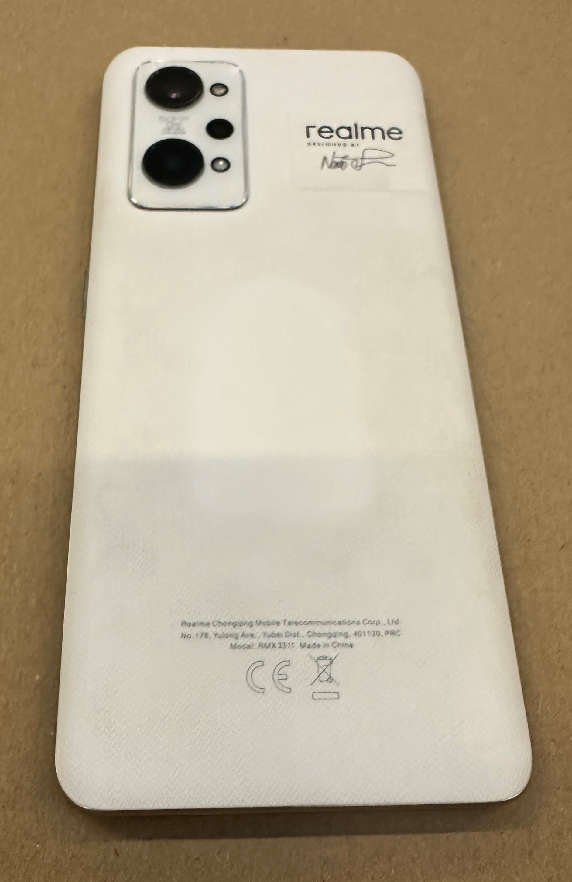 Tył białego smartfona Realme z obiektywem aparatu i napisem marki.