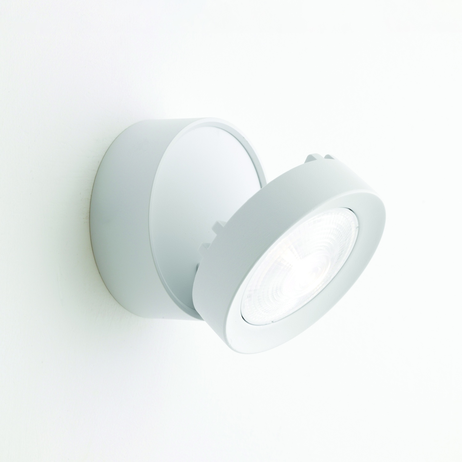Faretto grigio su muro bianco. La luce è accesa e angolata.