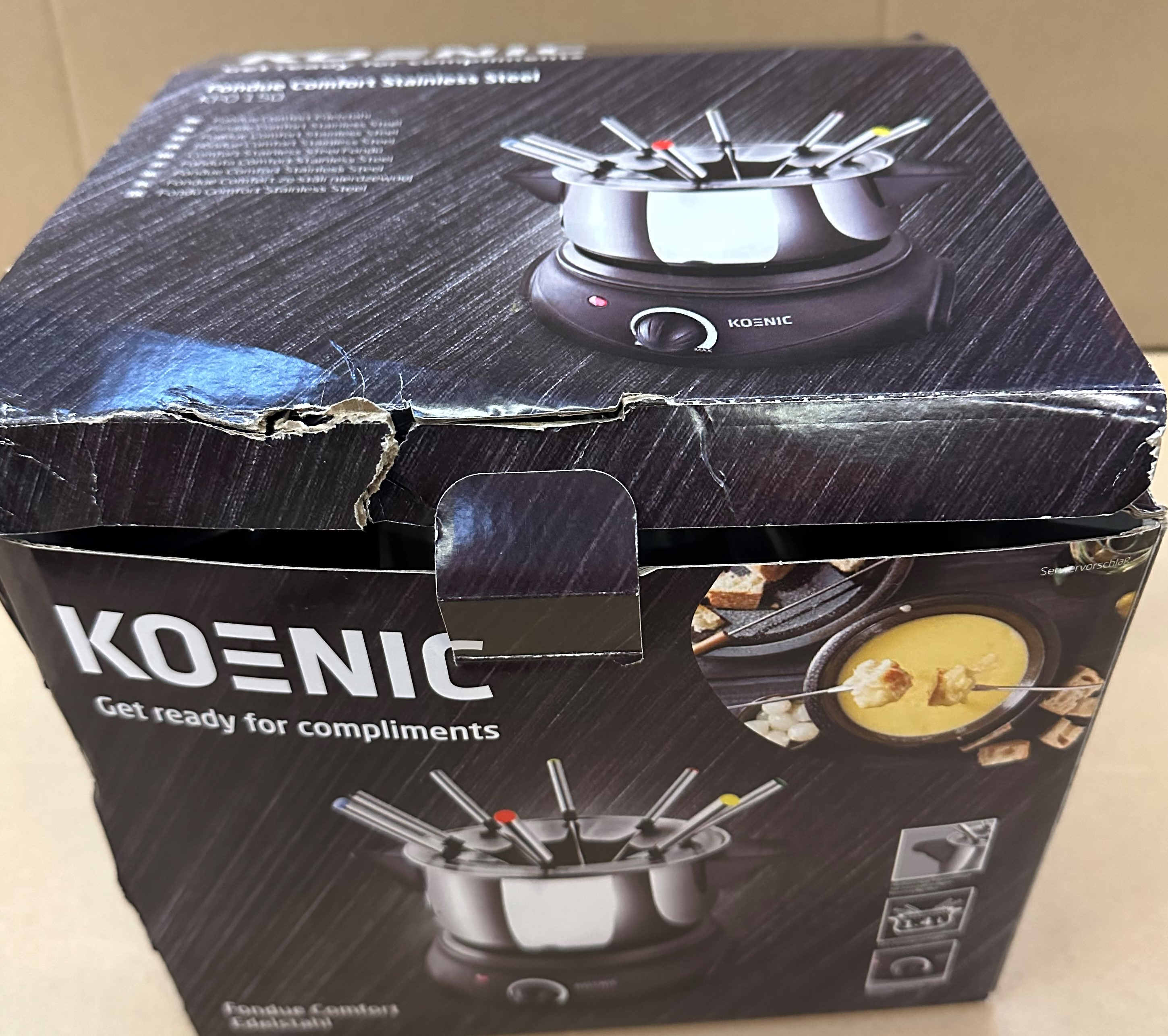 Pudełko zestawu do fondue Koenic, pokazujące produkt i logo Koenic, ze śladami uszkodzeń.