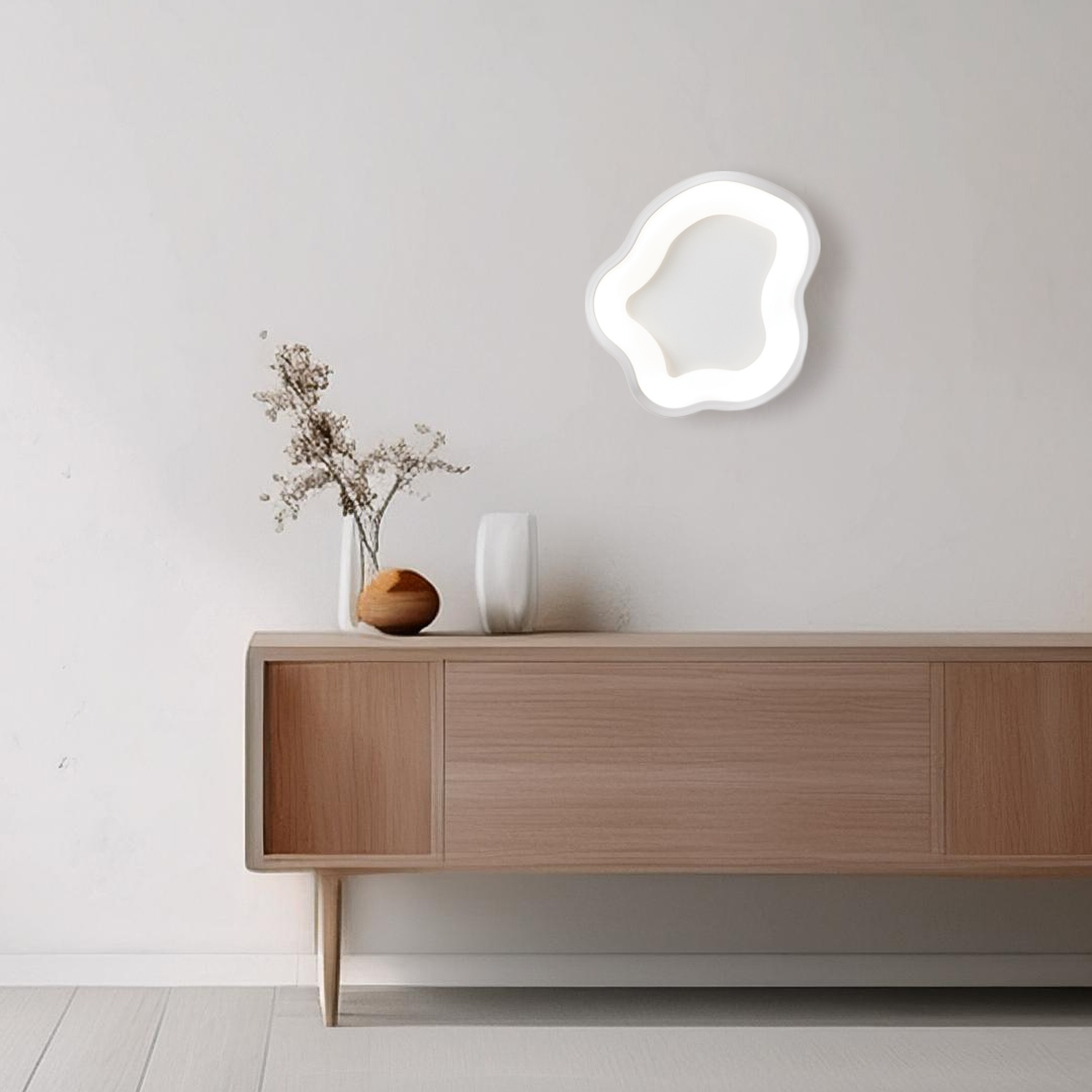 Parete bianca con lampada da parete moderna, bianca, a forma astratta e mobili in legno.