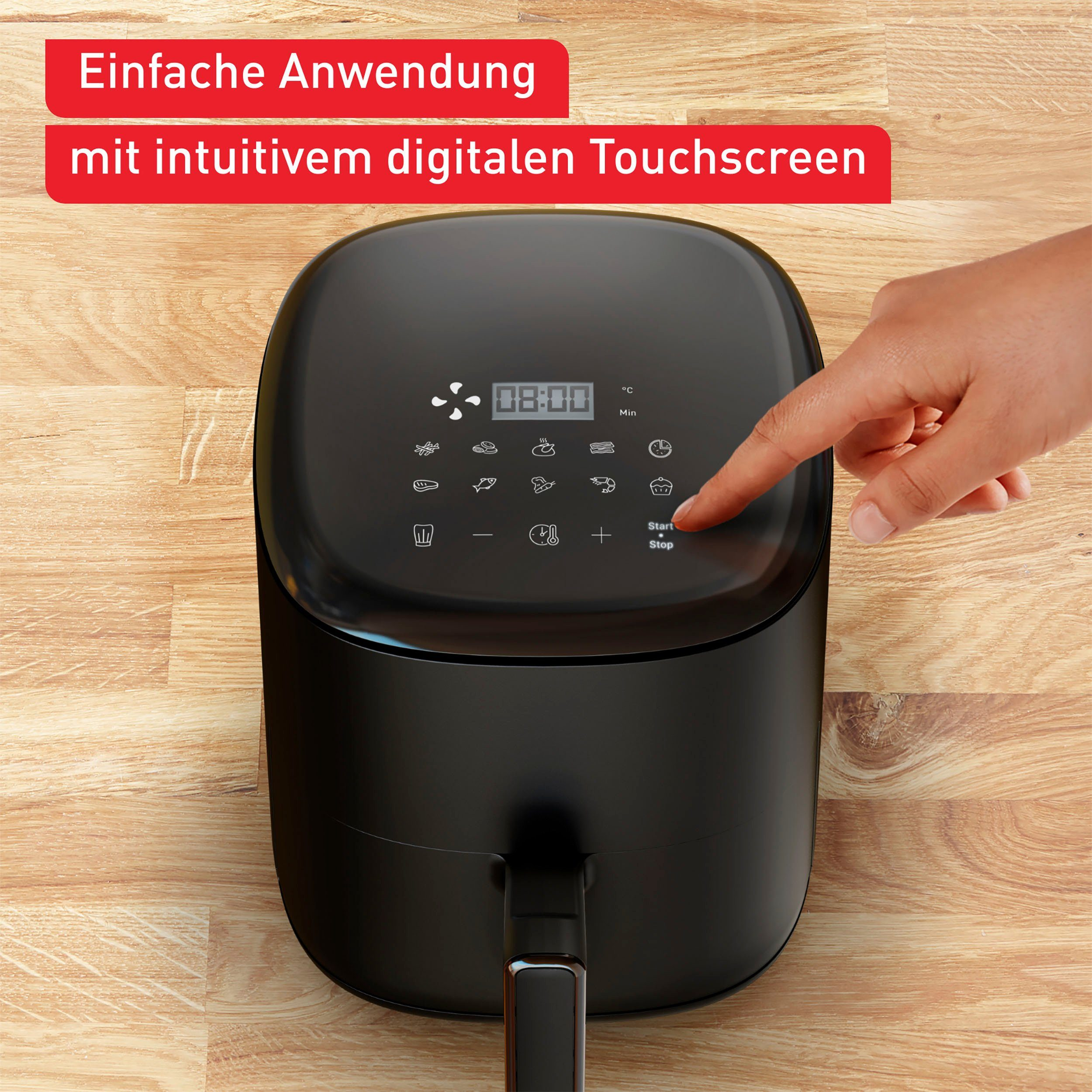 Schwarze Heißluftfritteuse. Hand berührt die Start-Taste auf einem digitalen Touchscreen. Holzuntergrund.