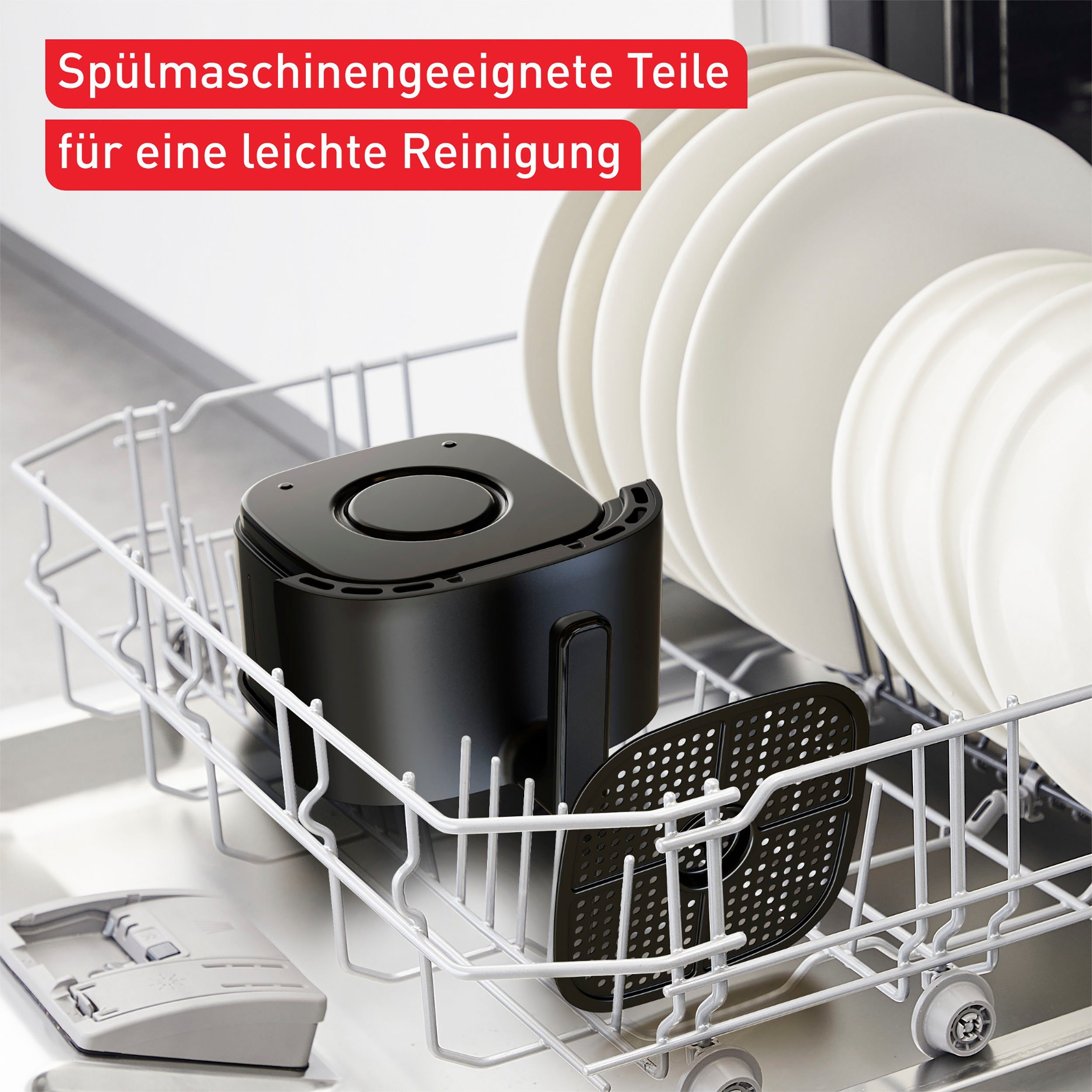 Geschirrspüler-Innenraum mit schwarzen Airfryer-Teilen und weißen Tellern.