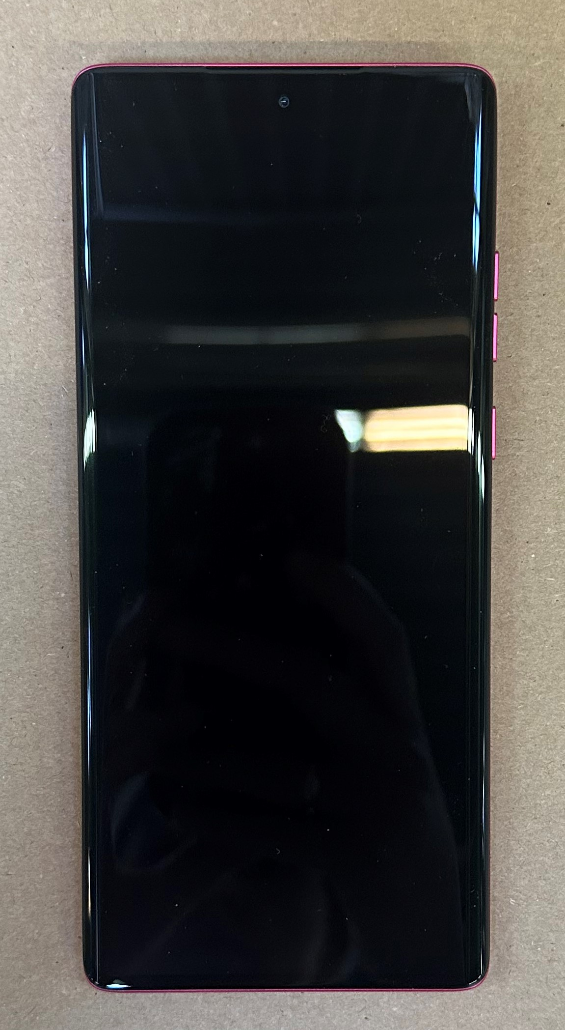 Czarny smartfon z różową ramką, aparat wyśrodkowany u góry.