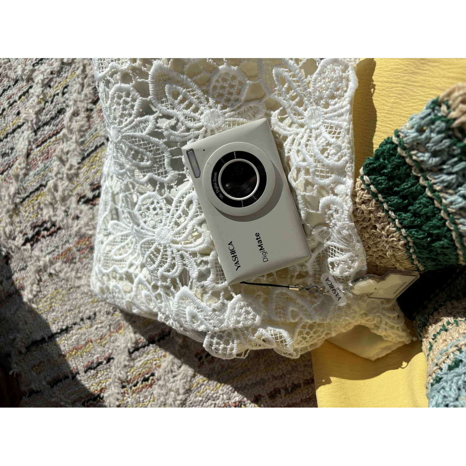 Grijze camera op een witte doek. Andere objecten, zoals een gele doek, zijn zichtbaar.