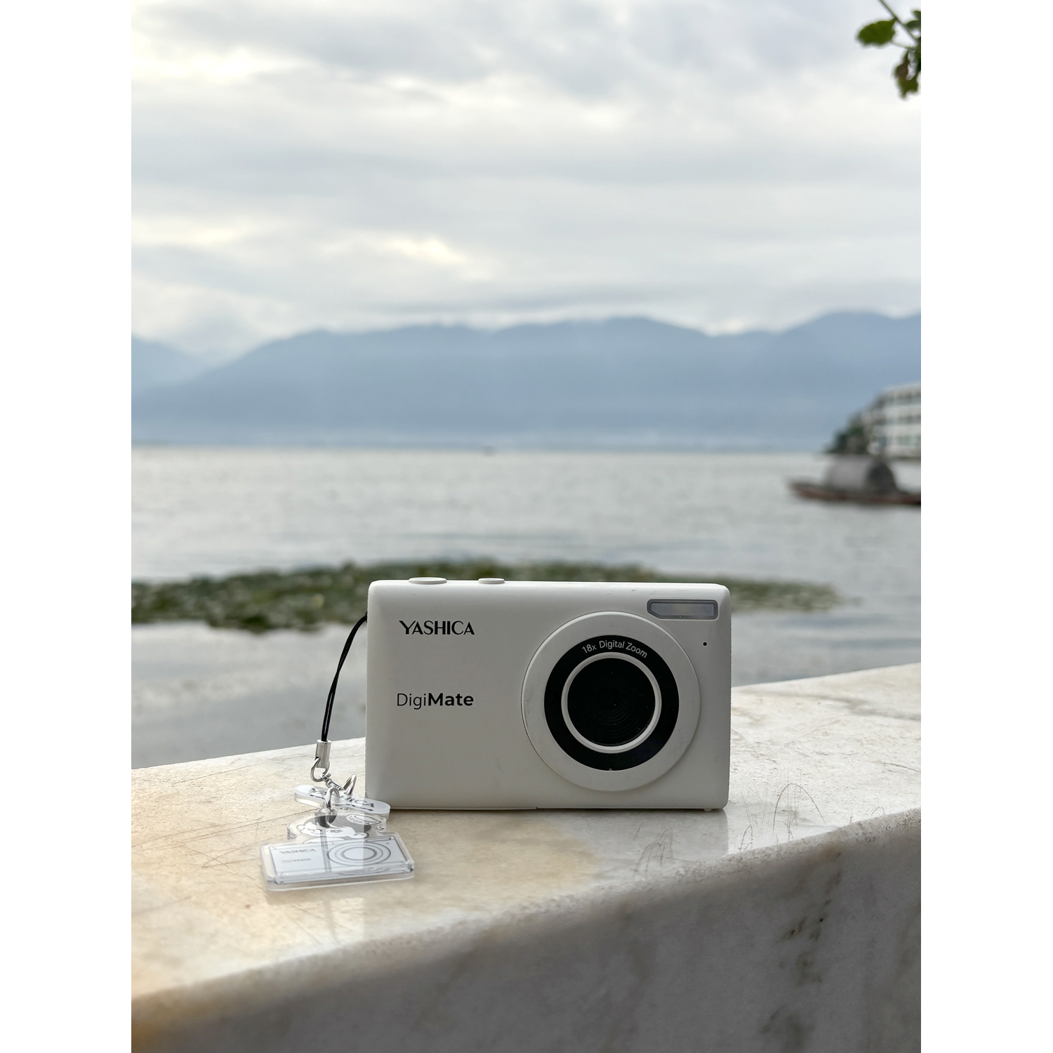 Een witte Yashica DigiMate camera op een stenen oppervlak bij het water.