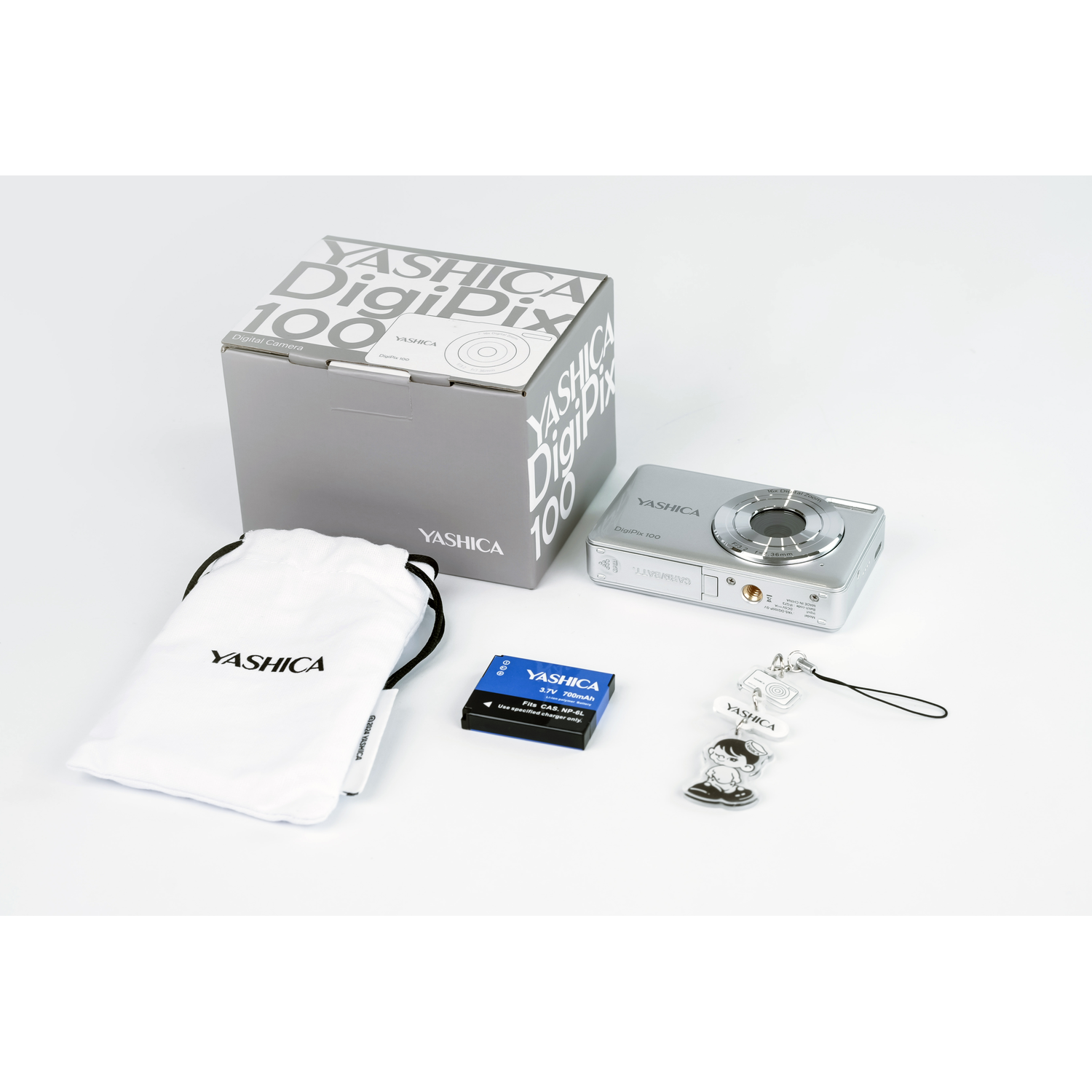 Silver YASHICA DigiPix 100 camera, box, pouch, battery, and charm on a white surface.