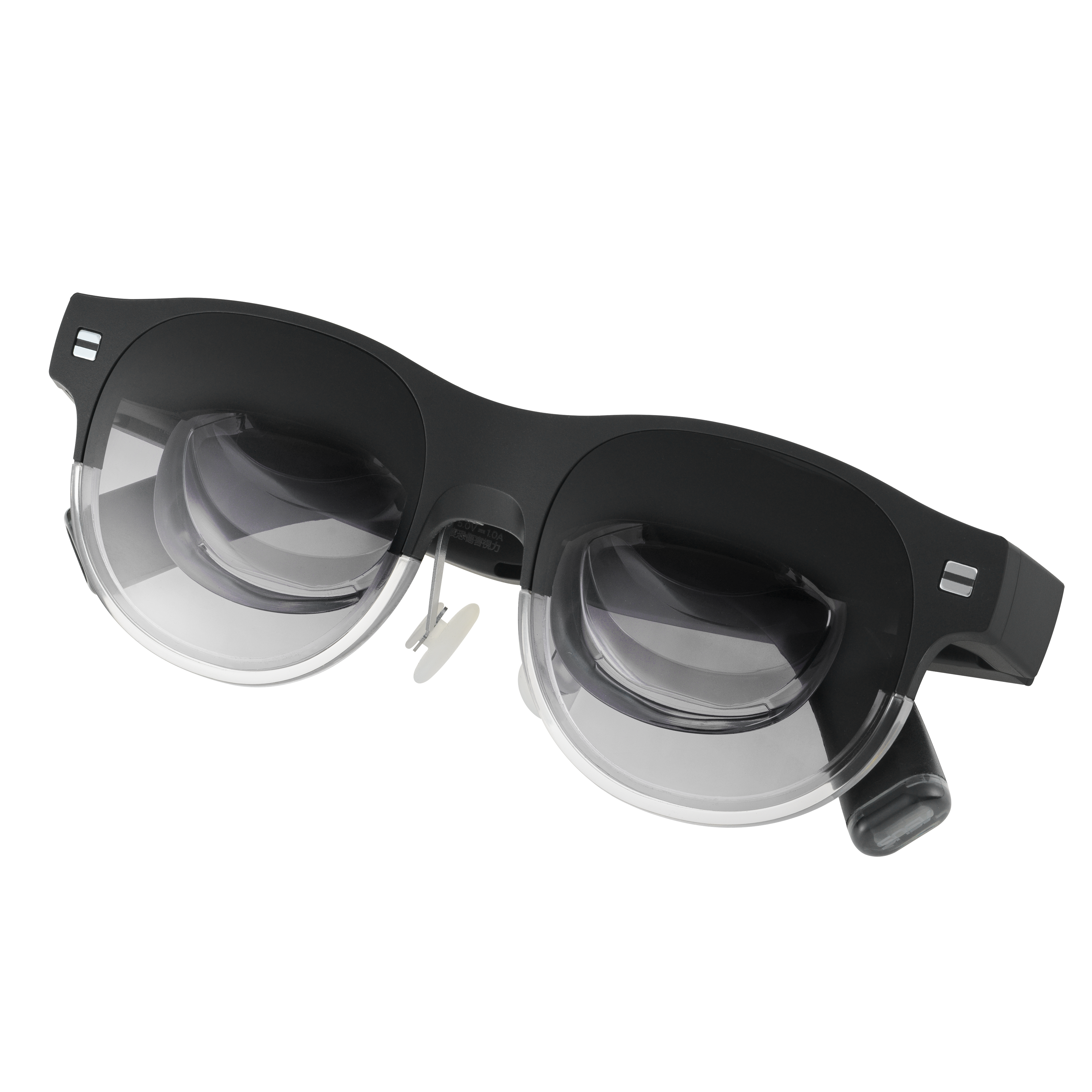 Schwarze VR-Brille mit klaren Gläsern. Die Brille liegt vor schwarzem Hintergrund.