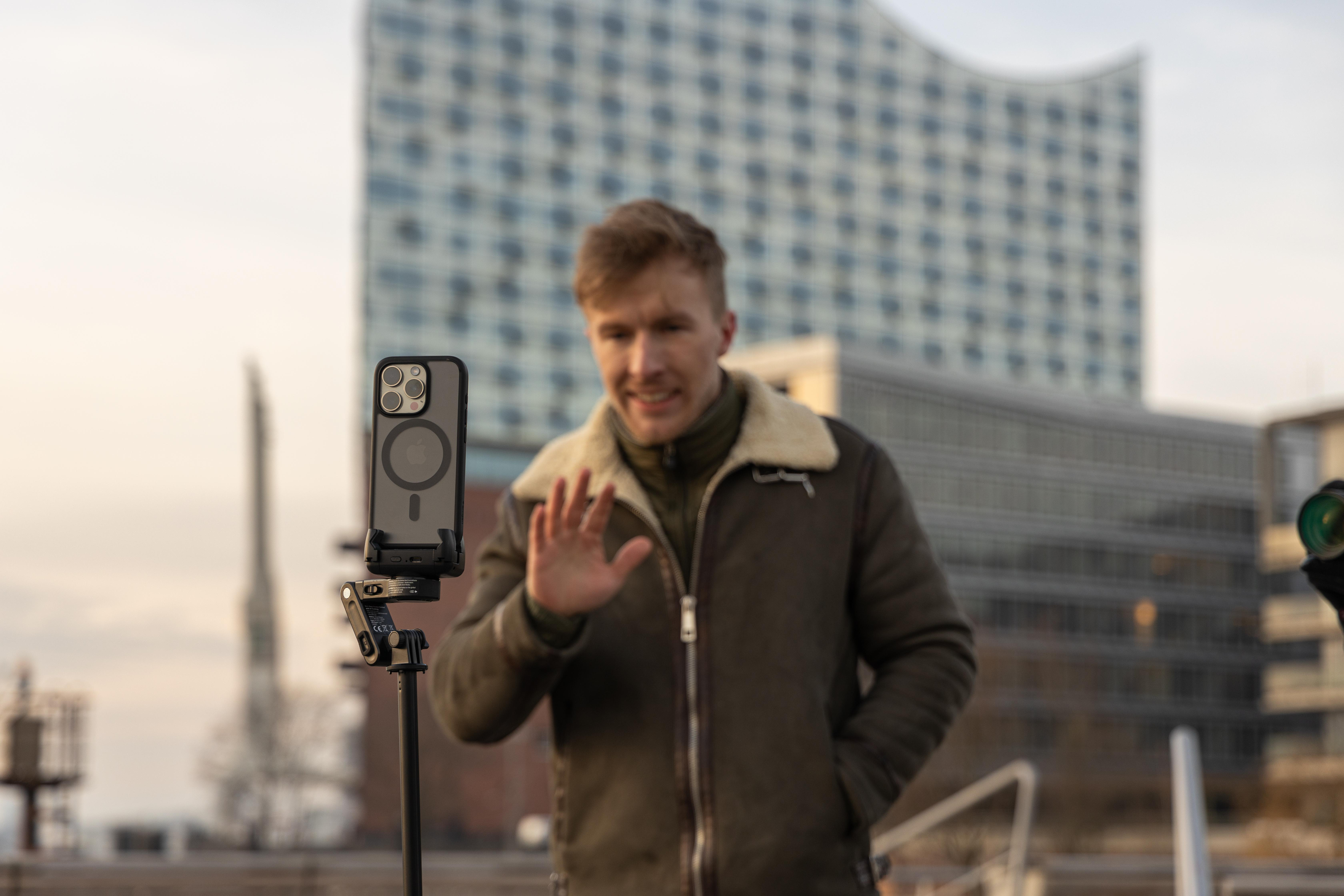Ein schwarzer Selfie-Stick mit Telefonhalter und Fernbedienung. Der Griff hat ein strukturiertes Muster.