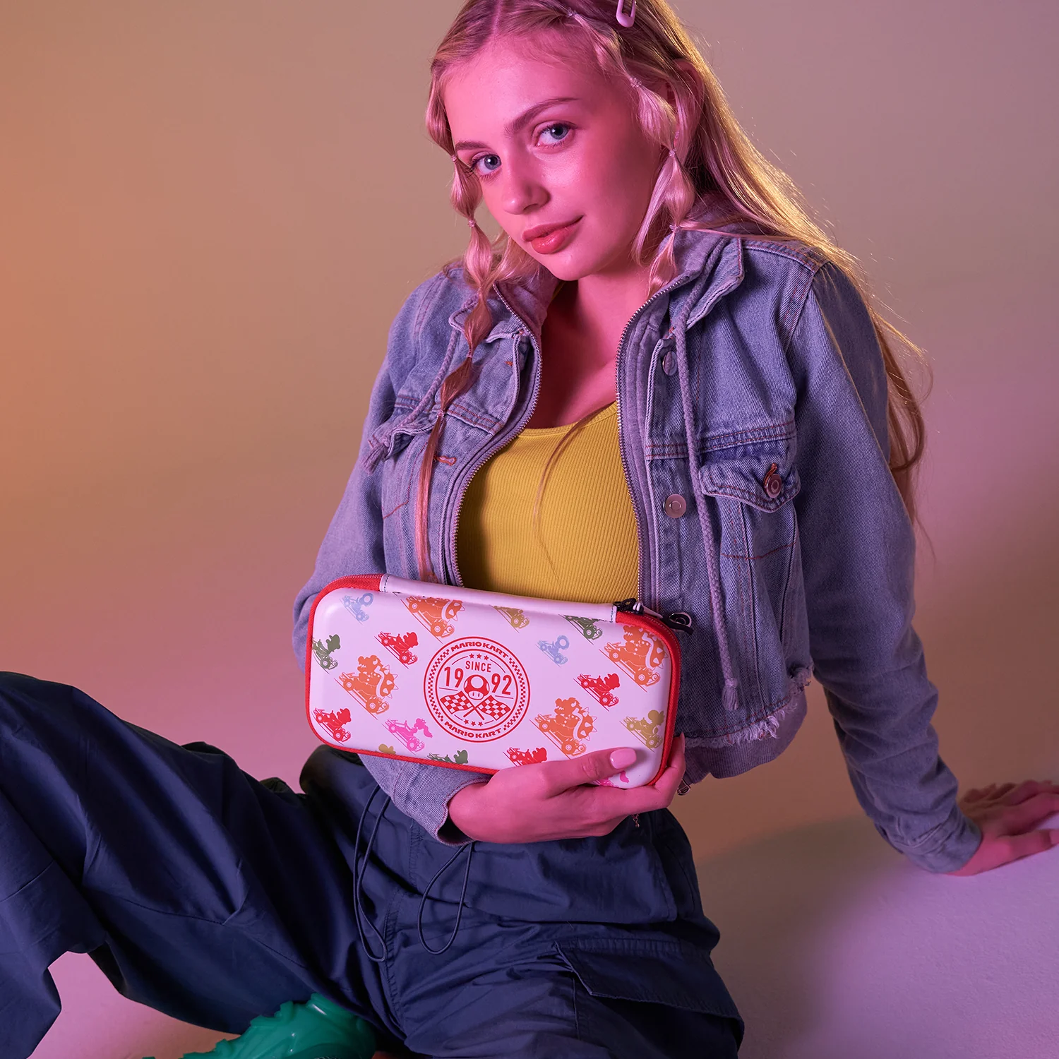 Frau hält Nintendo Switch-Hülle mit buntem Design, sitzt.