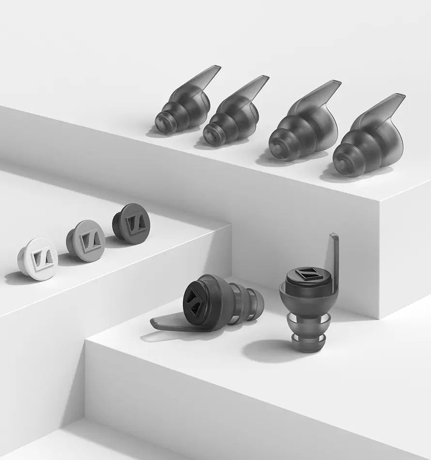 Bouchons d'oreille dans les tons gris, disposés sur une surface blanche.