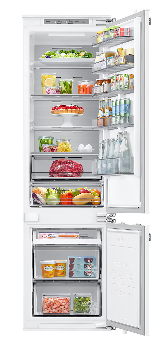 Lodówka z otwartymi drzwiami. Wnętrze wypełnione jest produktami spożywczymi i półkami. Biały kolor.