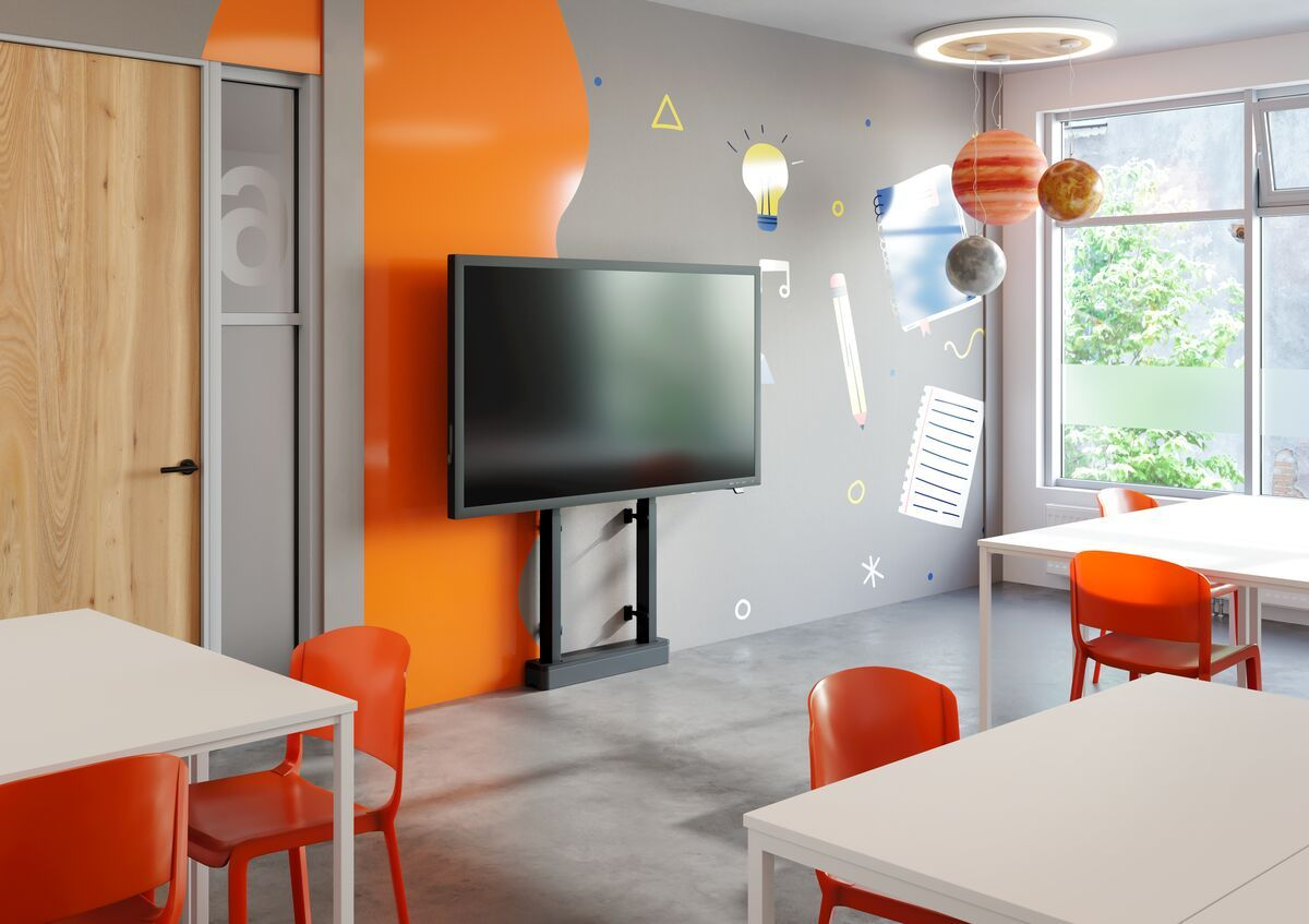 Klassenzimmerszene: Smartboard, rote Stühle, weiße Tische, bunte Wanddekorationen.
