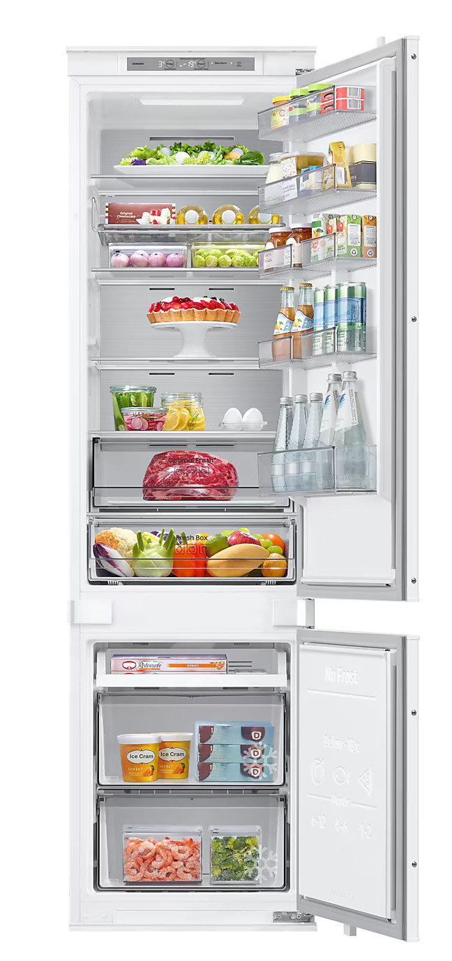 Otwarta lodówka wypełniona jedzeniem: owoce, warzywa, napoje i inne produkty, starannie ułożone.