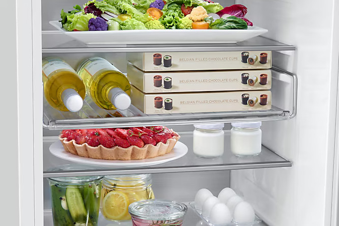 Wnętrze lodówki z półkami. Zawiera butelki wina, czekoladę, tartę owocową, jajka i słoiki.