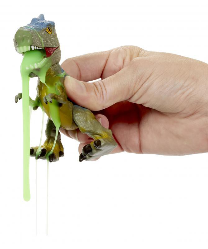 Eine Hand hält einen Spielzeug-Dinosaurier, aus dessen Mund grüner Schleim quillt. Weißer Hintergrund.