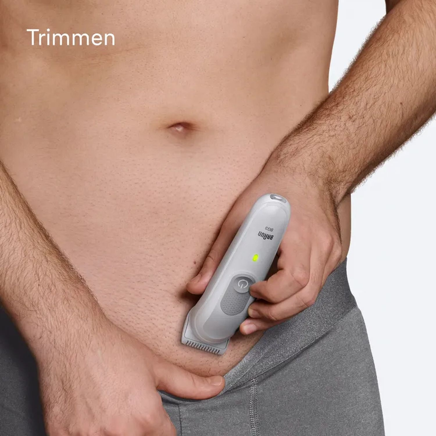Person trimming pubic hair with a Braun electric trimmer, in grey underwear.