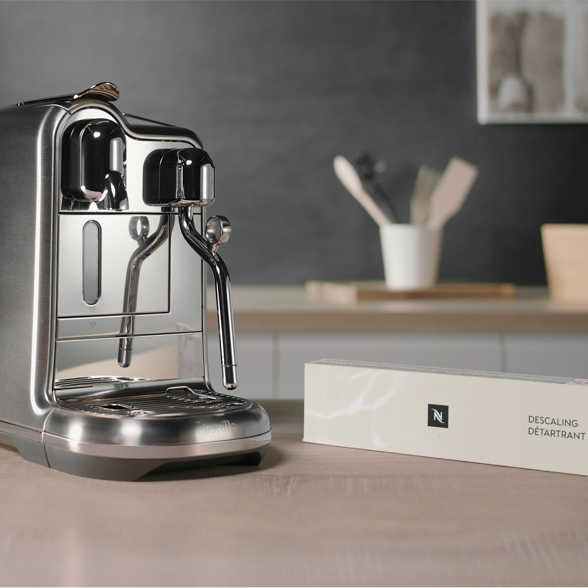 Eine Espressomaschine aus Edelstahl mit einer Entkalkungsmittelbox auf der Theke.