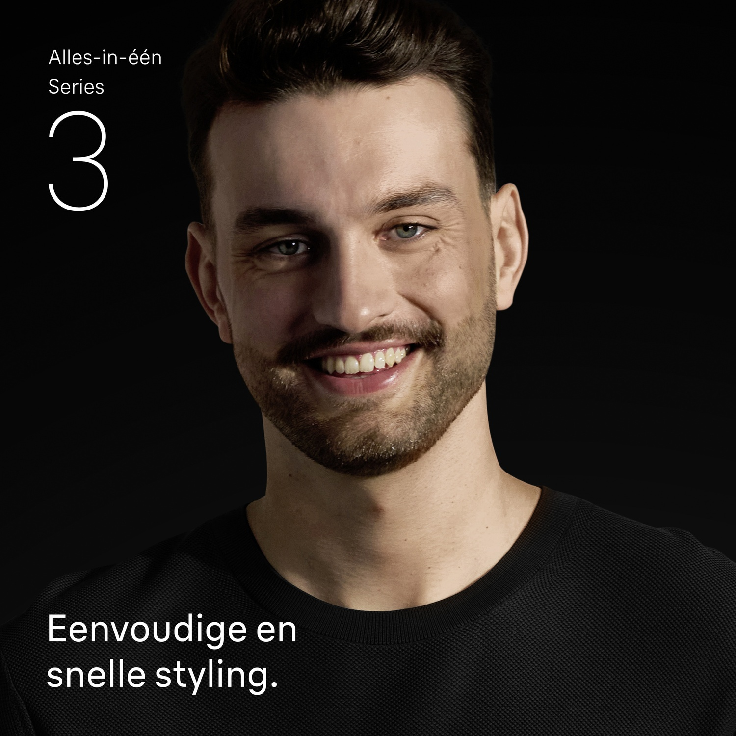 Smiling man with beard in black shirt on black background.