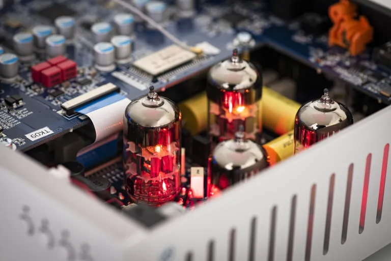 Glühende Vakuumröhren auf einer blauen Leiterplatte in einem elektronischen Gerät.