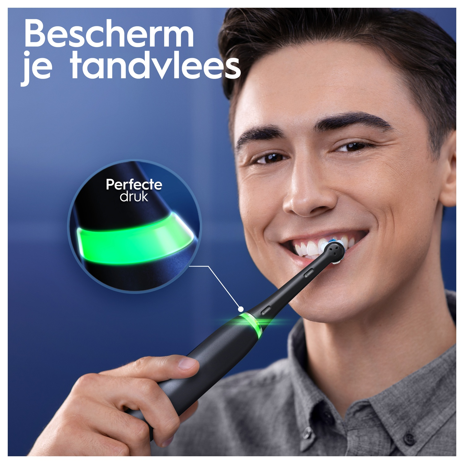 A man smiles while holding an electric toothbrush near his mouth.